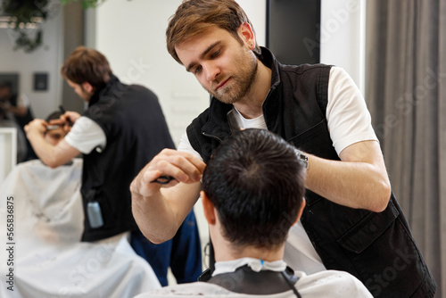 hairdresser does haircut for caucasian bearded man