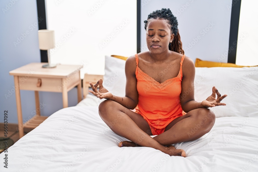 African american woman doing yoga exercise sitting on bed at bedroom African american woman doing yoga exercise sitting on bed at bedroom