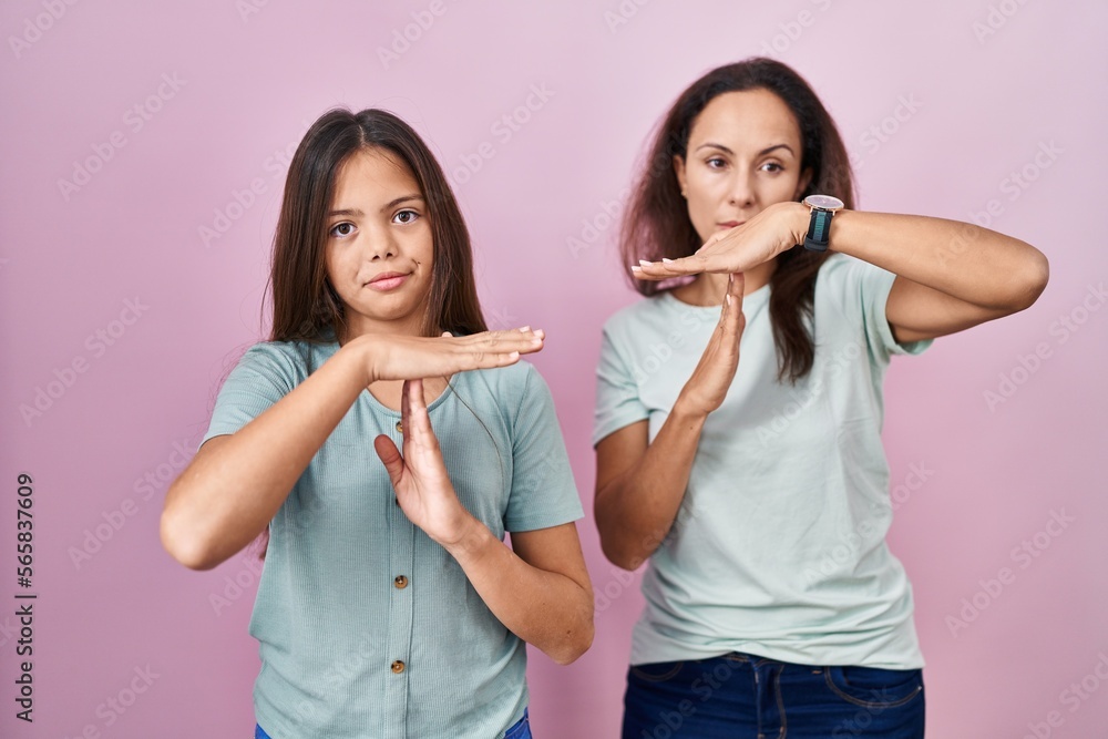 Young mother and daughter standing over pink background doing time out gesture with hands, frustrated and serious face Young mother and daughter standing over pink background doing time out gesture with hands, frustrated and serious face