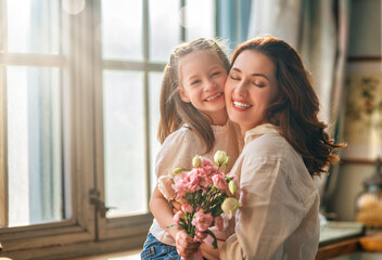 Daughter giving mother bouquet of flowers.