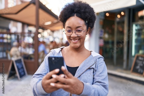 African american woman smiling confident using smartphone at coffee shop terrace