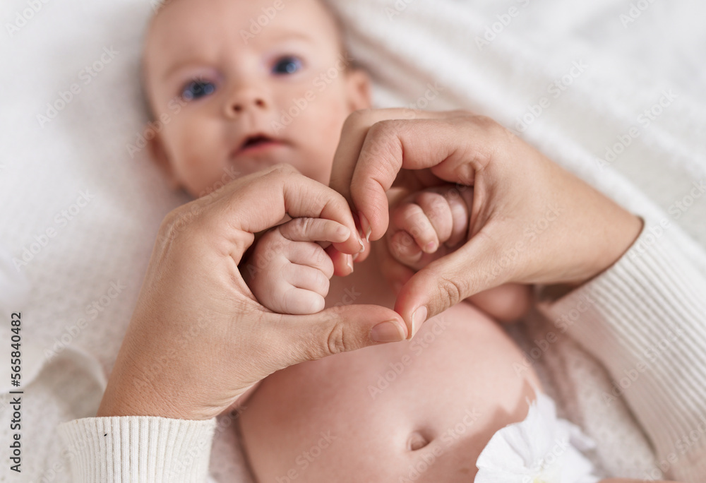 Adorable caucasian baby lying on bed with holding mother hands at bedroom Adorable caucasian baby lying on bed with holding mother hands at bedroom