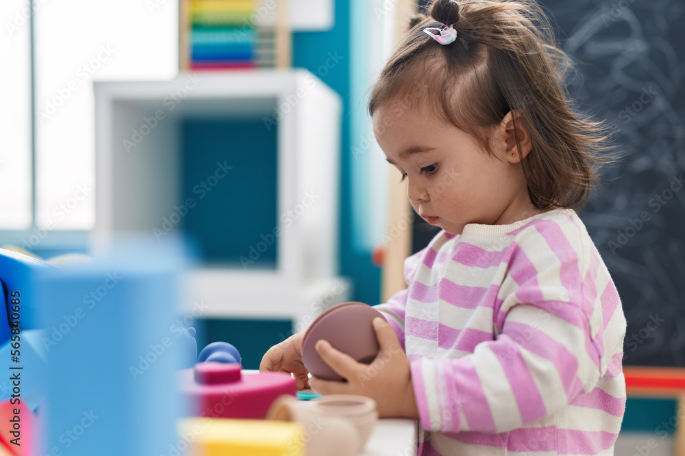 Adorable chinese toddler playing with toys standing at kindergarten Adorable chinese toddler playing with toys standing at kindergarten