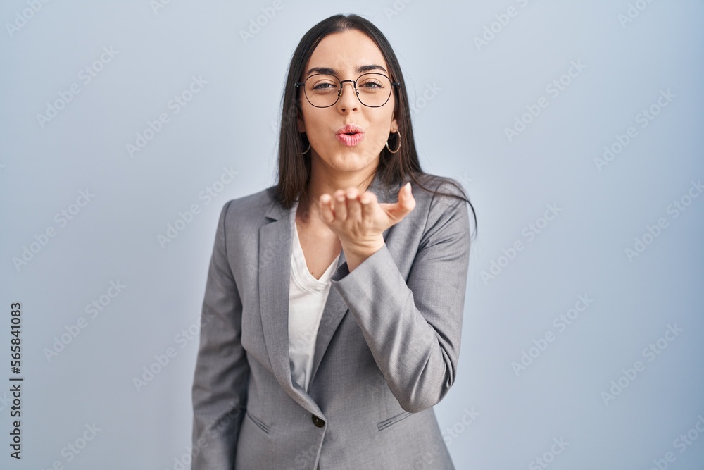 Hispanic business woman wearing glasses looking at the camera blowing a kiss with hand on air being lovely and sexy. love expression. Hispanic business woman wearing glasses looking at the camera blowing a kiss with hand on air being lovely and sexy. love expression.