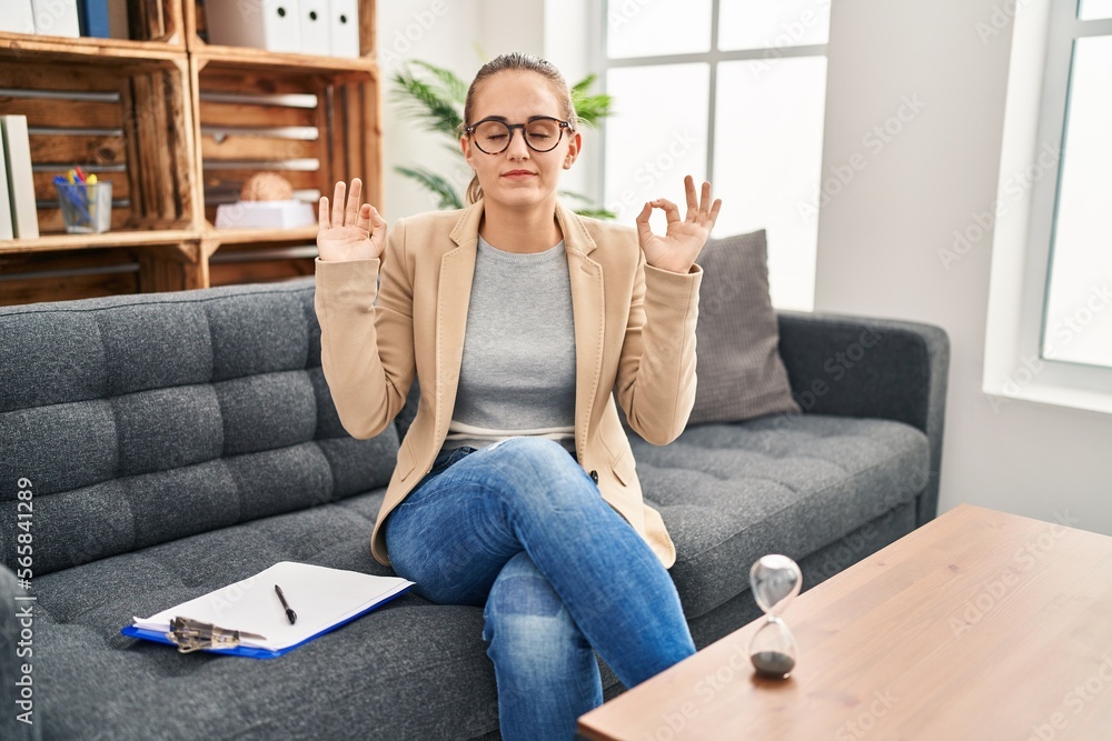 Young woman working at consultation office relaxed and smiling with eyes closed doing meditation gesture with fingers. yoga concept. Young woman working at consultation office relaxed and smiling with eyes closed doing meditation gesture with fingers. yoga concept.