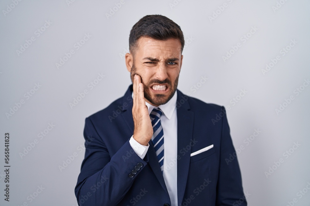 Handsome hispanic man wearing suit and tie touching mouth with hand with painful expression because of toothache or dental illness on teeth. dentist Handsome hispanic man wearing suit and tie touching mouth with hand with painful expression because of toothache or dental illness on teeth. dentist