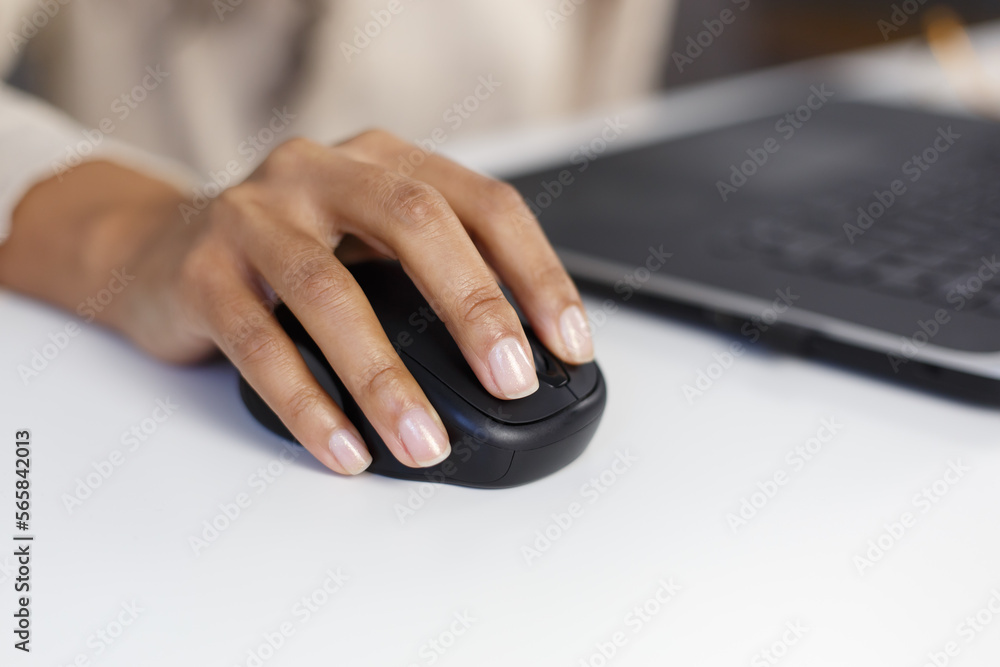 BIPOC woman works on computer in an office. Black female clicking with wireless computer mouse in closeup BIPOC woman works on computer in an office. Black female clicking with wireless computer mouse in closeup