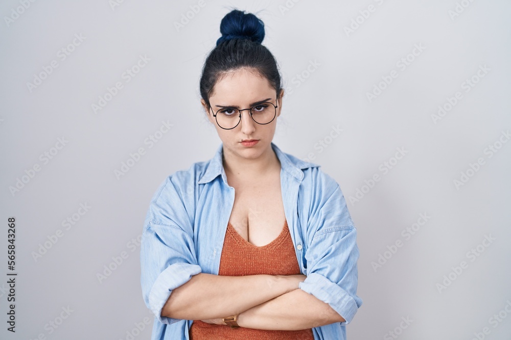 Obraz premium Young modern girl with blue hair standing over white background skeptic and nervous, disapproving expression on face with crossed arms. negative person.
