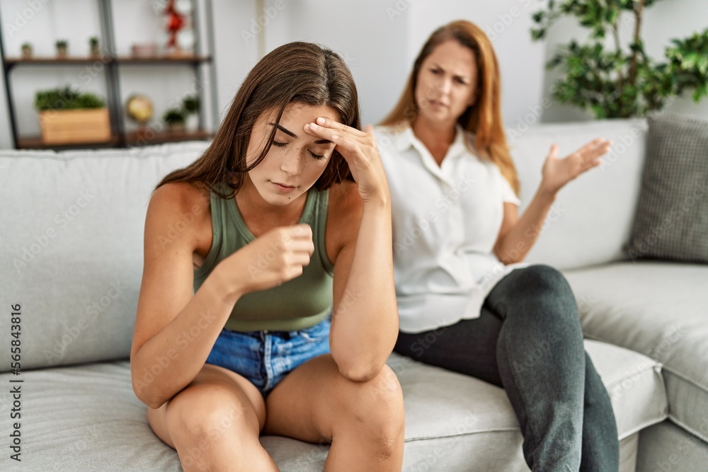 Mother and daughter unhappy arguing sitting on sofa at home Mother and daughter unhappy arguing sitting on sofa at home
