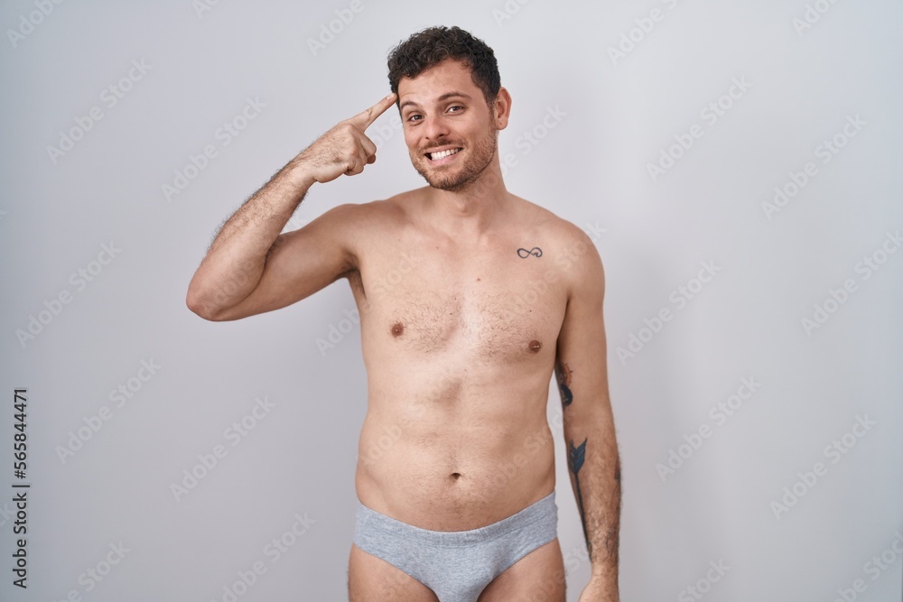Young hispanic man standing shirtless wearing underware smiling pointing to head with one finger, great idea or thought, good memory