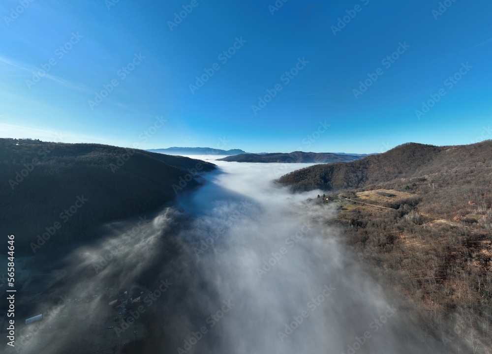 Aerial View. Flying over the high mountains in beautiful clouds. Aerial Drone camera shot. Air pollution clouds over Sarajevo in Bosnia and Herzegovina. 