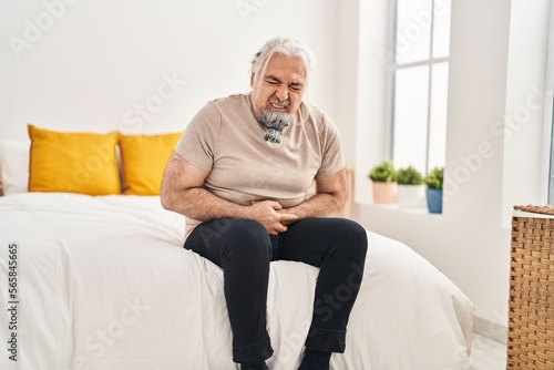 Middle age grey-haired man suffering for stomach ache sitting on bed at bedroom © Krakenimages.com