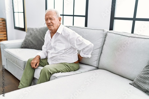 Senior man suffering for backache sitting on sofa at home