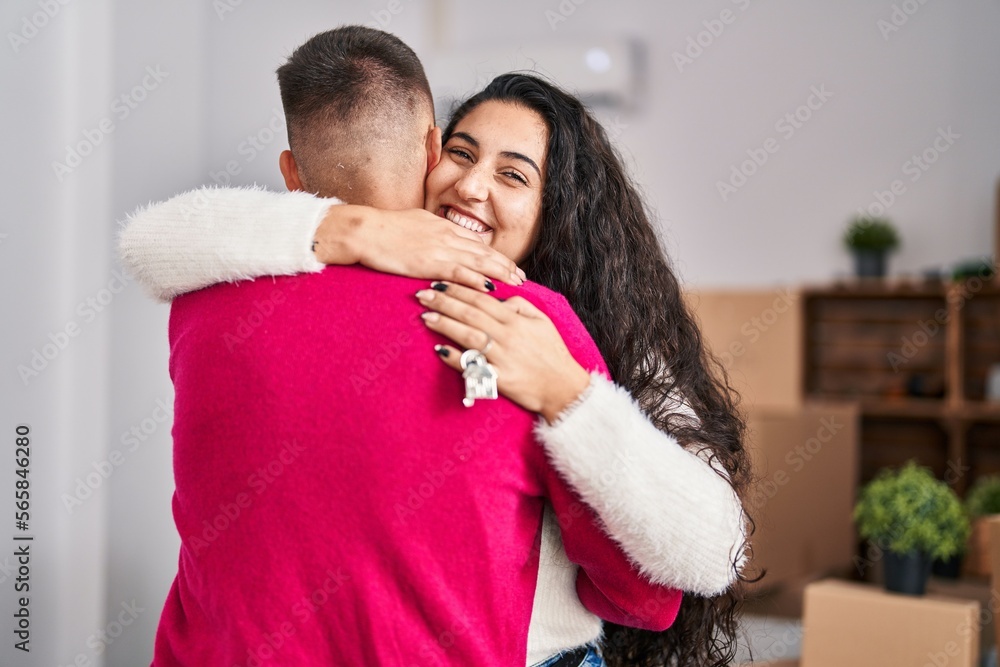Man and woman couple hugging each other holding key at new home Man and woman couple hugging each other holding key at new home