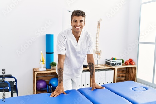 Young hispanic man working as physiotherapist at physiotherapy room