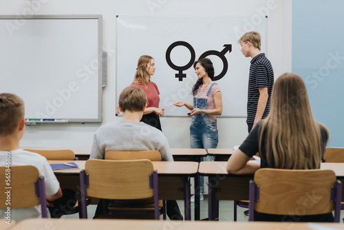 Young teacher is standing in front of the blackboard during sex education lesson