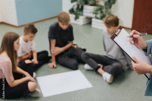 Group of teenagers sit in a circle on the floor and prepare a project together
