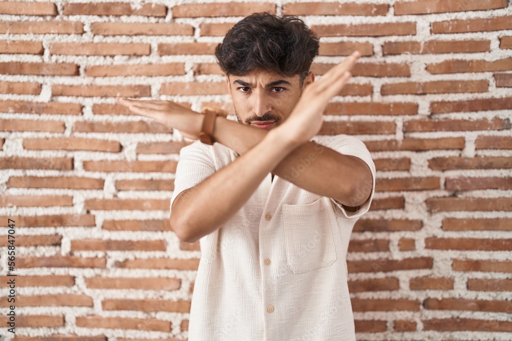 Arab man with beard standing over bricks wall background rejection expression crossing arms doing negative sign, angry face Arab man with beard standing over bricks wall background rejection expression crossing arms doing negative sign, angry face