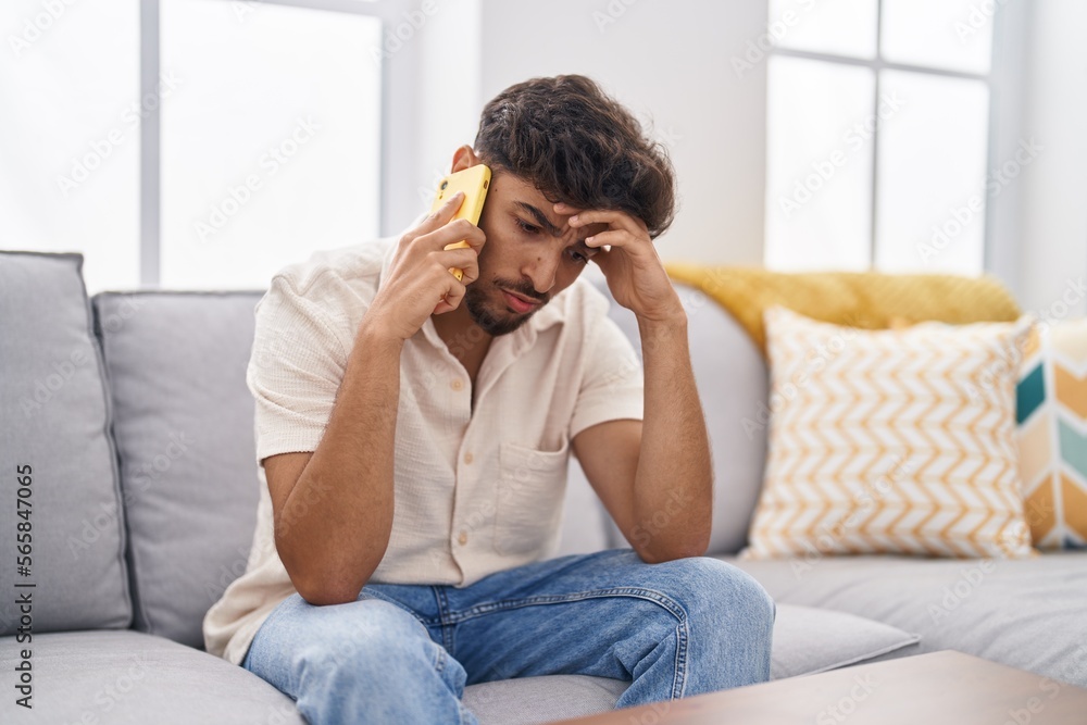 Young arab man talking on the smartphone with worried expression at home Young arab man talking on the smartphone with worried expression at home