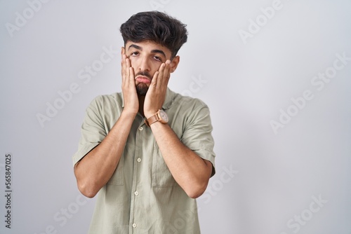 Arab man with beard standing over white background tired hands covering face  depression and sadness  upset and irritated for problem