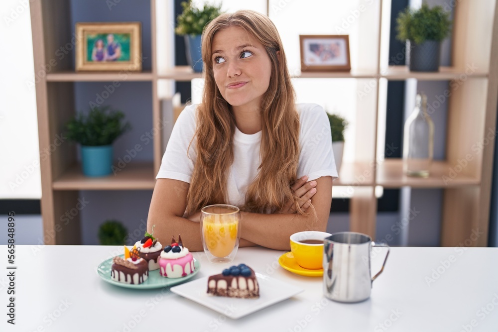 Young caucasian woman eating pastries t for breakfast smiling looking to the side and staring away thinking.