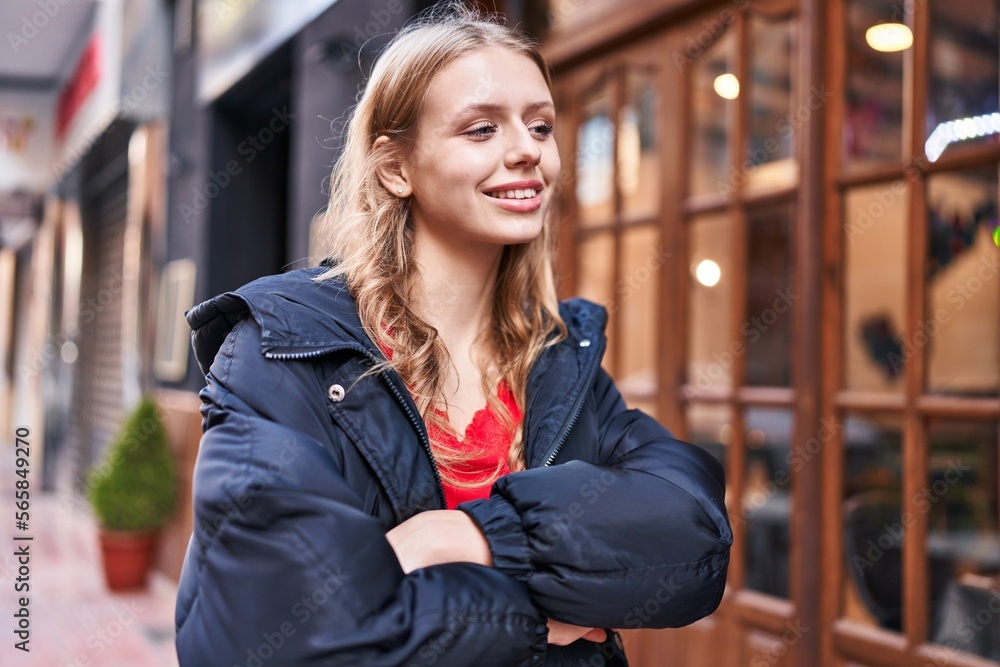 Young blonde woman looking to the side with arms crossed gesture at street