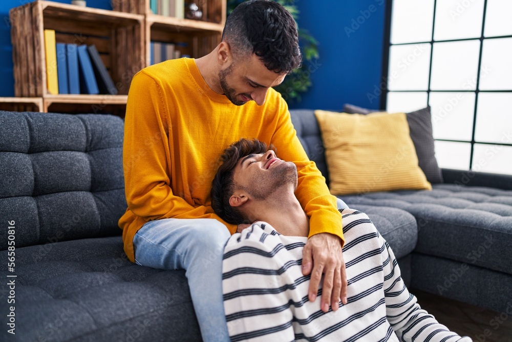 Obraz premium Two man couple hugging each other sitting on sofa at home