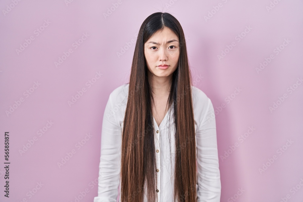 Chinese young woman standing over pink background depressed and worry for distress, crying angry and afraid. sad expression. Chinese young woman standing over pink background depressed and worry for distress, crying angry and afraid. sad expression.