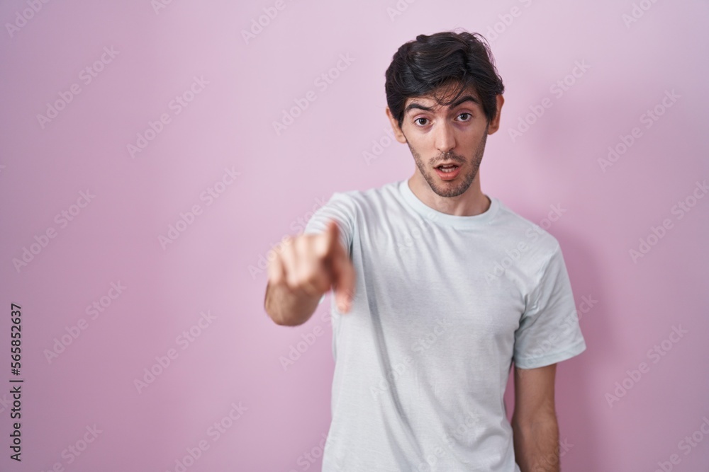 Young hispanic man standing over pink background pointing displeased and frustrated to the camera, angry and furious with you Young hispanic man standing over pink background pointing displeased and frustrated to the camera, angry and furious with you