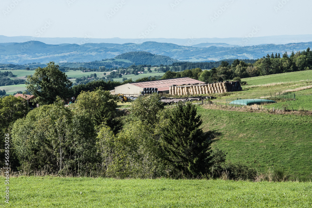 view on a farm with hay bales in the green valleys of the mountain region of the Auvergne