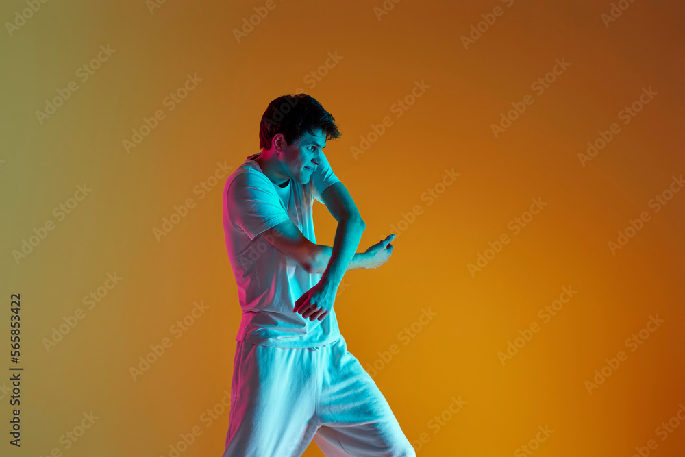 man dancing on yellow background. Neon lighting