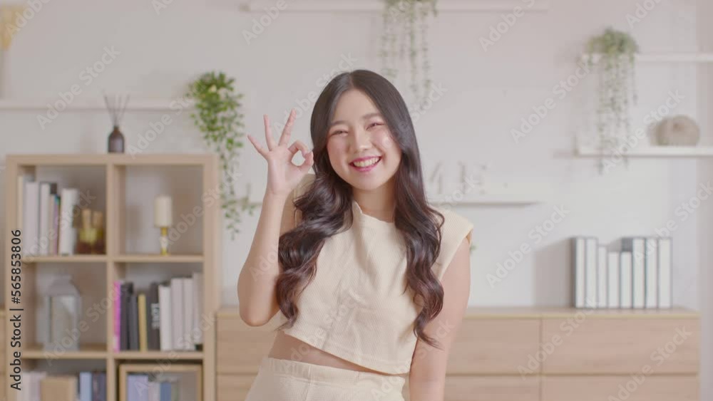 Beautiful young Asian woman showing thumbs up OK gesture smile with positive emotional at home. Attractive female making okay hand sign or say yes happiness and cheerful. Women lifestyle concept Beautiful young Asian woman showing thumbs up OK gesture smile with positive emotional at home. Attractive female making okay hand sign or say yes happiness and cheerful. Women lifestyle concept