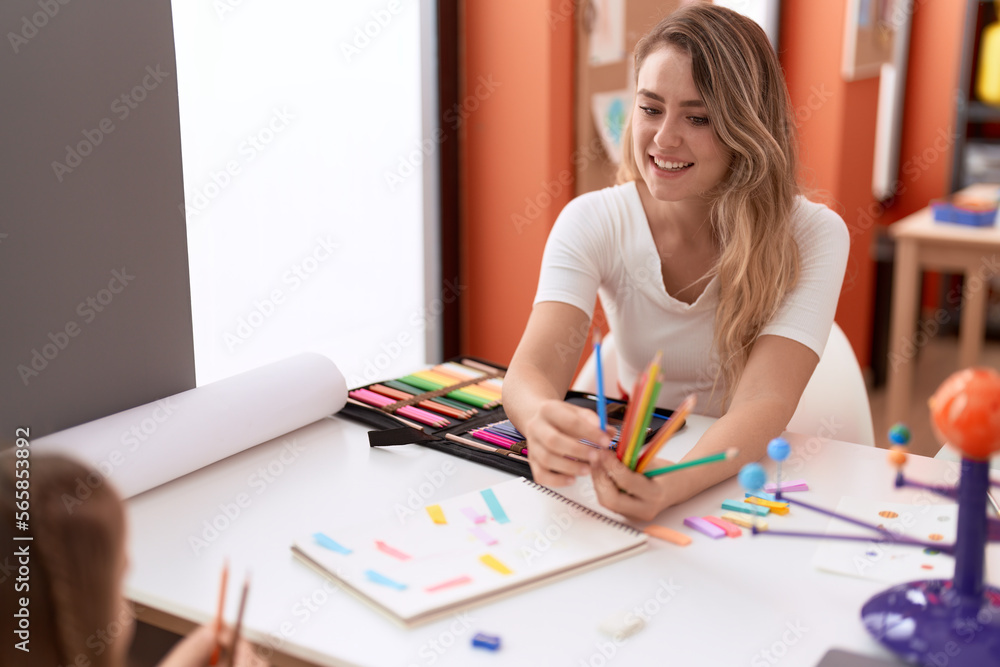 Teacher and toddler having planets lesson holding color pencils at classroom Teacher and toddler having planets lesson holding color pencils at classroom