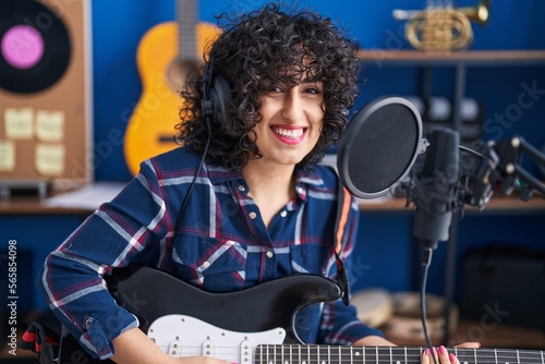 Young middle east woman artist singing song playing electrical guitar at music studio