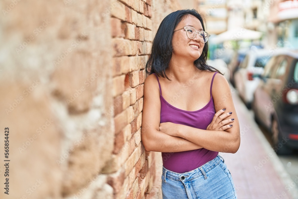 Young chinese woman standing with arms crossed gesture at street