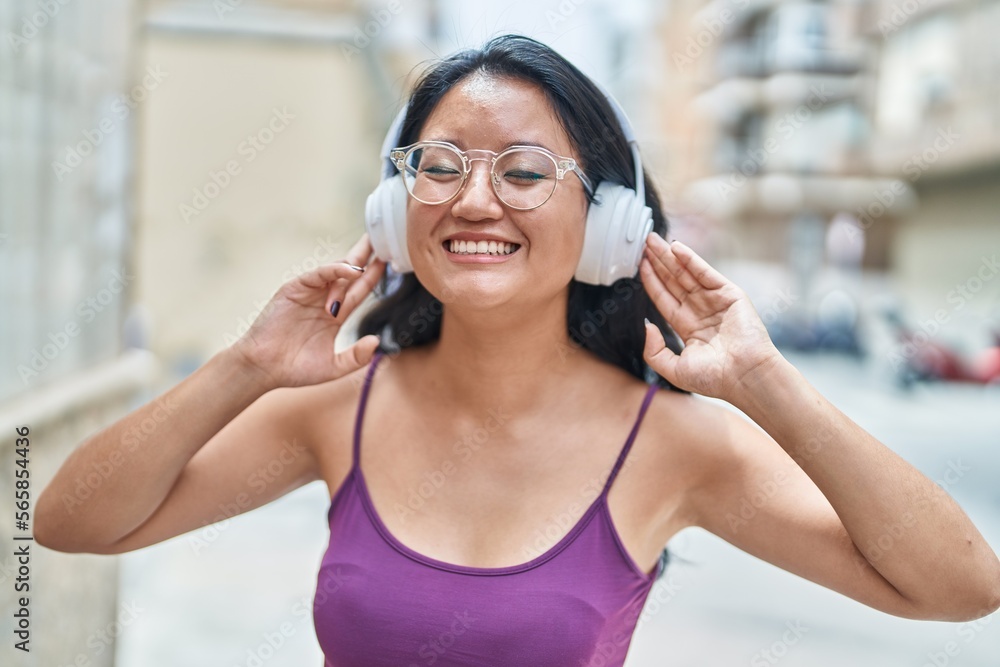 Young chinese woman listening to music and dancing at street
