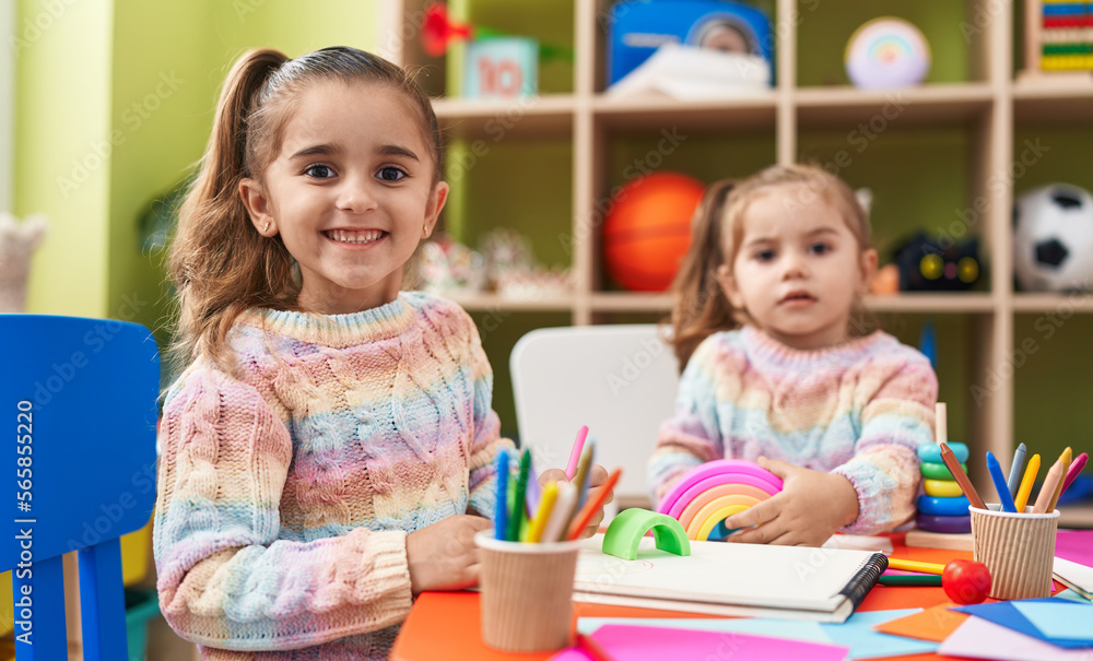 Fototapeta premium Two kids preschool students sitting on table drawing on paper at kindergarten