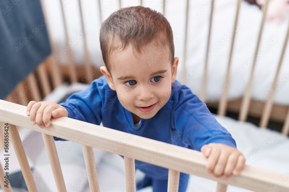 Adorable hispanic toddler smiling confident standing on cradle at bedroom Adorable hispanic toddler smiling confident standing on cradle at bedroom