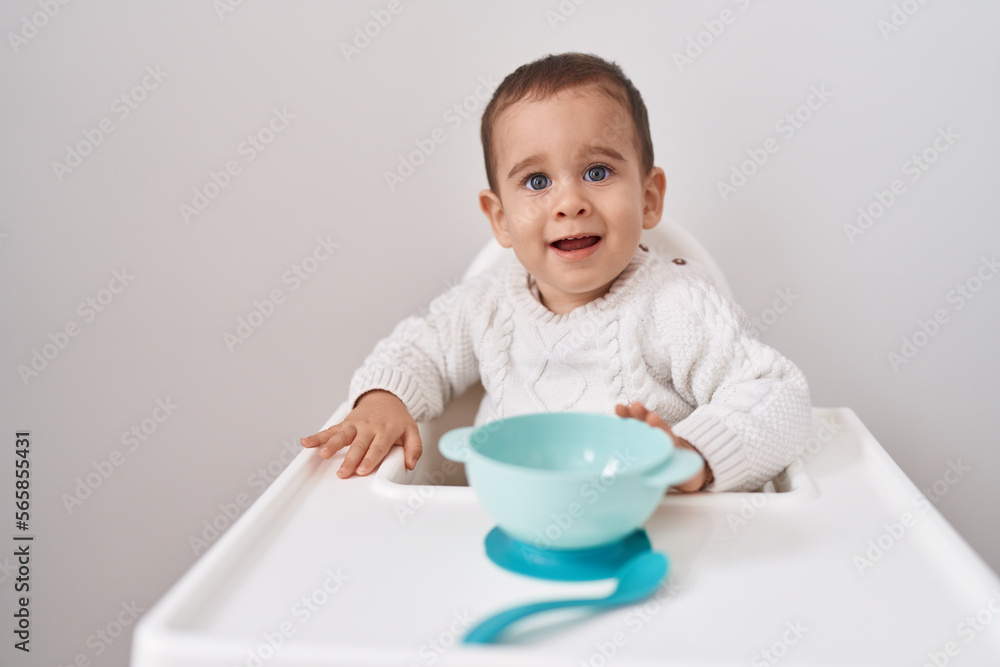 Adorable hispanic toddler smiling confident sitting on highchair over isolated white background Adorable hispanic toddler smiling confident sitting on highchair over isolated white background