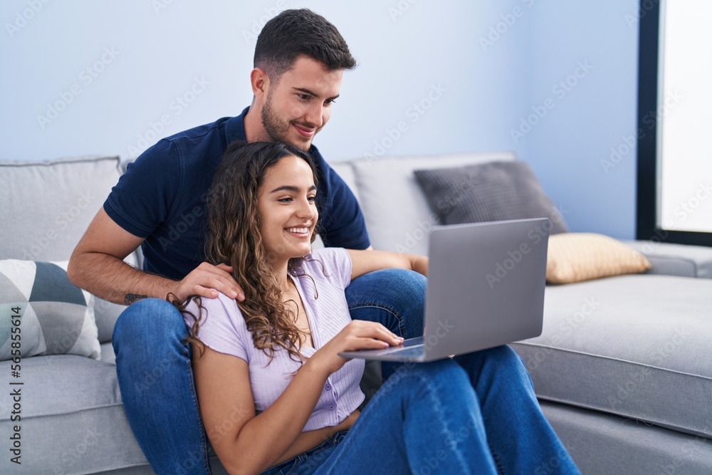 Young hispanic couple using laptop sitting on sofa at home Young hispanic couple using laptop sitting on sofa at home