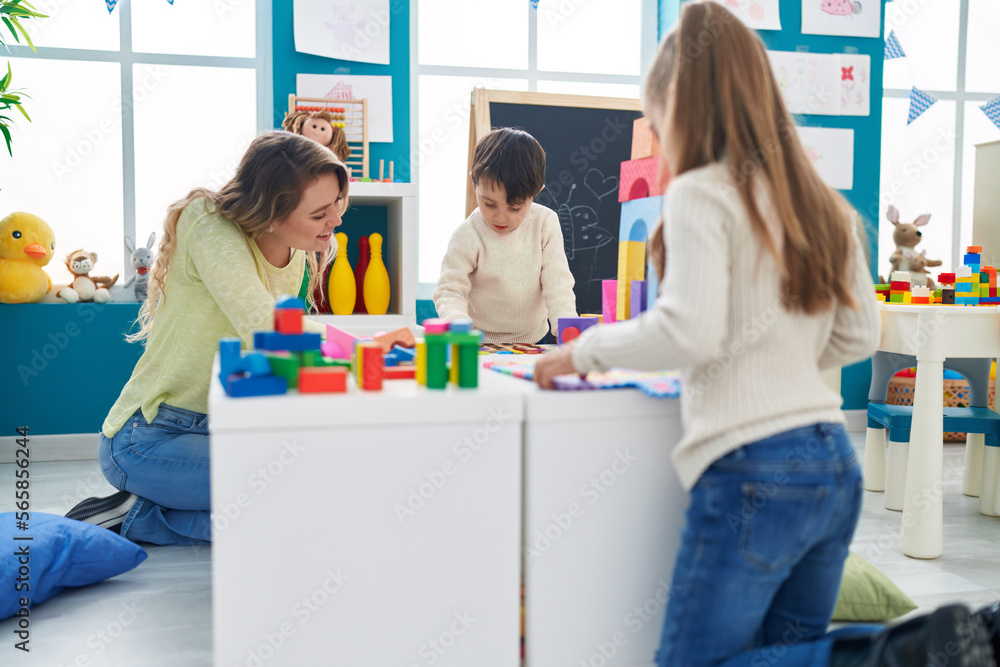 Group of kids playing with maths puzzle game with teacher at kindergarten Group of kids playing with maths puzzle game with teacher at kindergarten