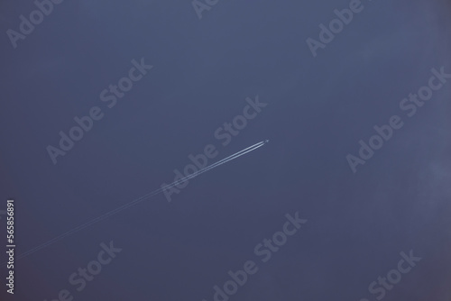 Aereo da trasporto passeggeri in alta quota con scie bianche provenienti dai motori. Sfondo di cielo blu. photo