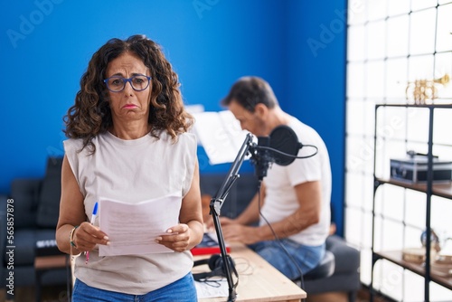 Middle age hispanic woman singing at music studio depressed and worry for distress, crying angry and afraid. sad expression.