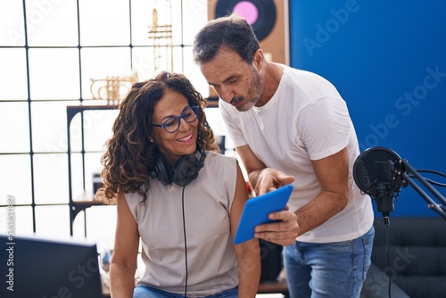 Man and woman musicians composing song using computer and touchpad at music studio photo