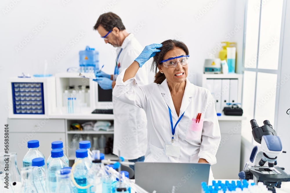 Middle age woman working at scientist laboratory stressed and frustrated with hand on head, surprised and angry face Middle age woman working at scientist laboratory stressed and frustrated with hand on head, surprised and angry face