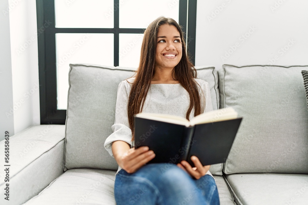 Young latin woman reading book sitting on sofa at home Young latin woman reading book sitting on sofa at home