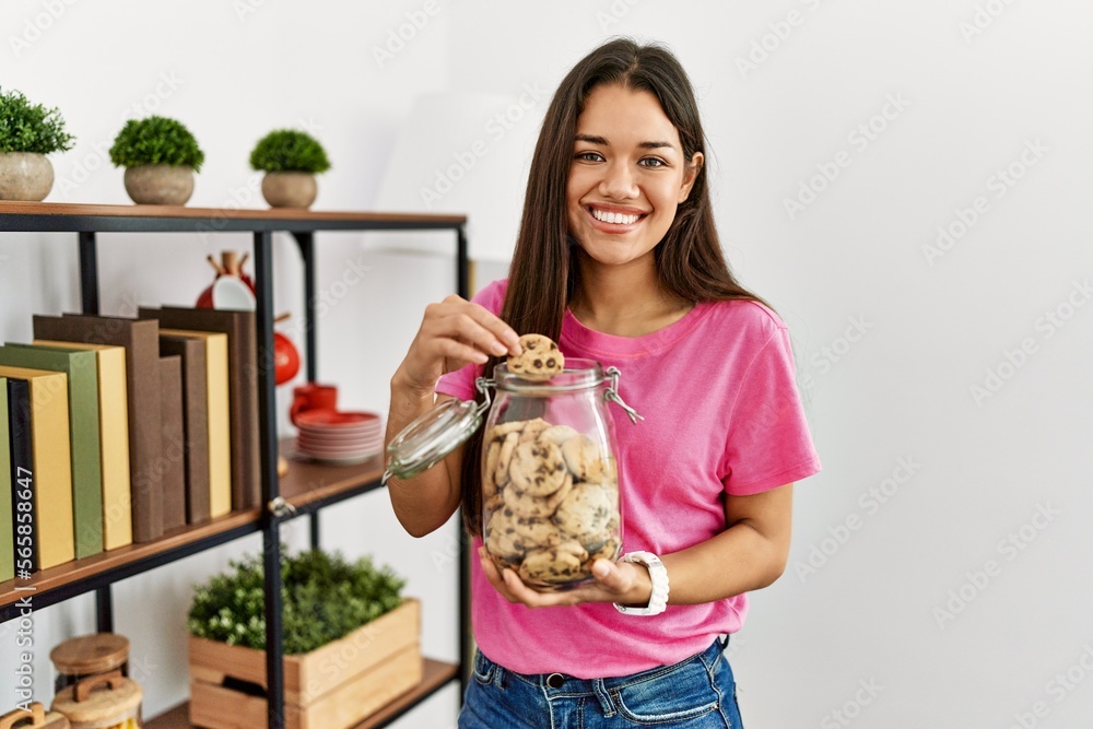 Young latin woman smiling confident eating cookies at home Young latin woman smiling confident eating cookies at home