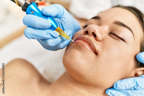 Young latin woman relaxed having microblading lips treatment at beauty center