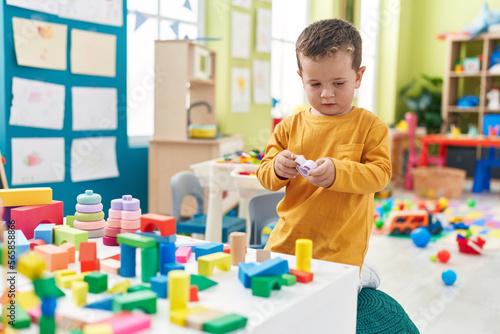 Adorable caucasian boy playing with toys sitting on floor at kindergarten