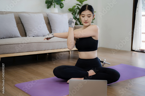 Female using laptop during workout at home. Online personal trainer or on laptop.